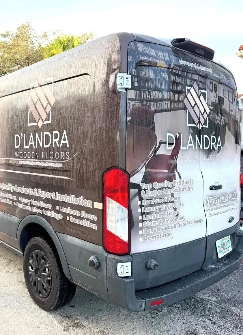 D'Landra Wooden Floors mobile showroom van in a wood-grain wrap, parked on a South Florida driveway